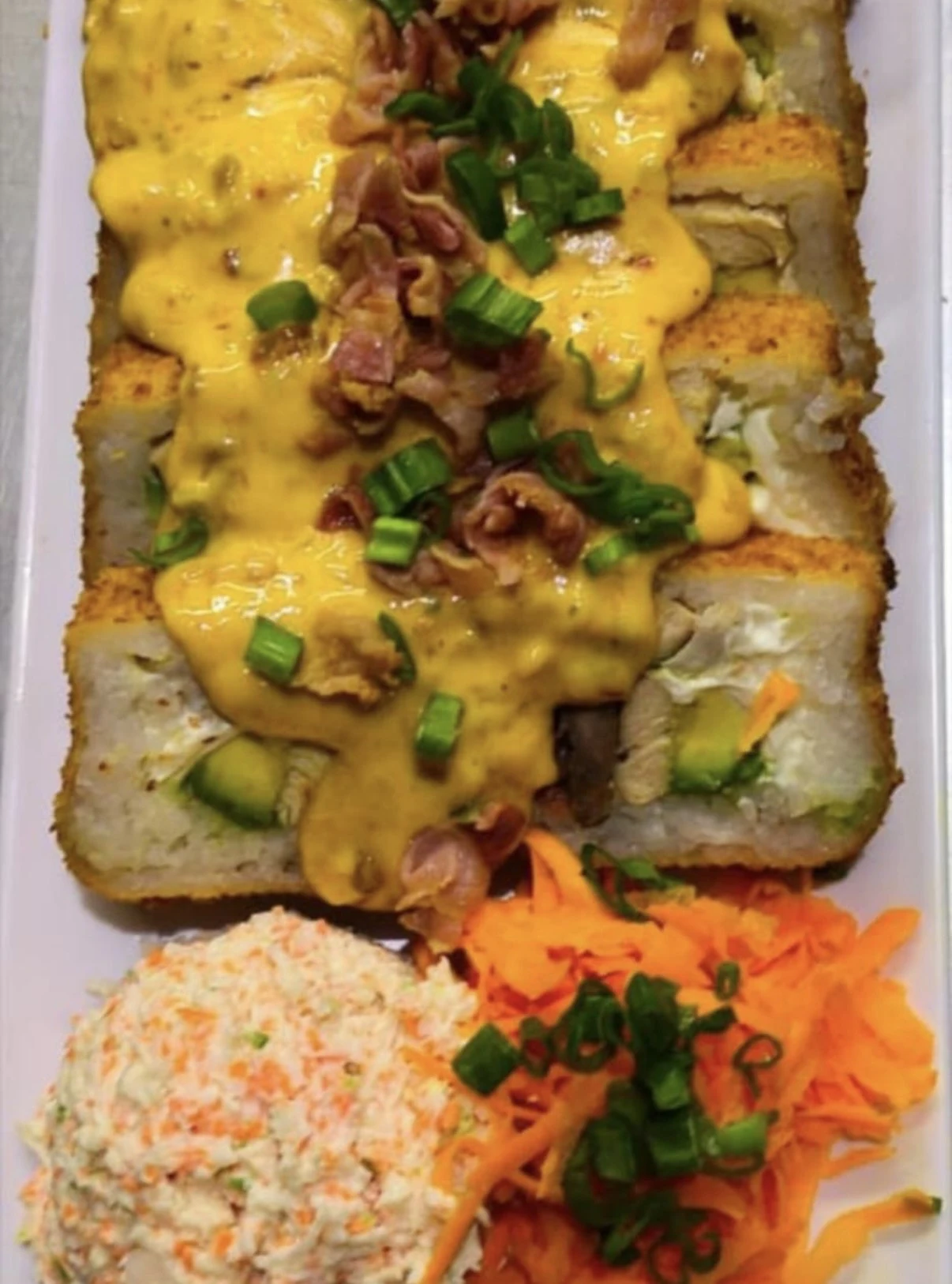 Sushi bañado en salsa de queso con tocino y cebollín